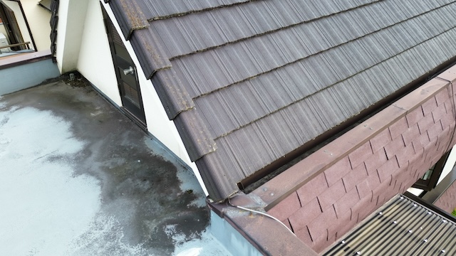 日本瓦の屋根と陸屋根（防水面）の接続部分。異なる屋根材が接する「取り合い」は雨水が浸入しやすい弱点となるため、隙間や立ち上がり部分を入念に確認している。