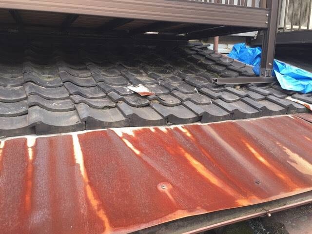 ベランダ下のトタン屋根に発生した著しい赤錆と腐食。雨漏り応急処置のブルーシート養生と、ガルバリウム鋼板への葺き替え提案用写真。