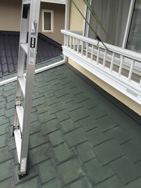 梯子での高所作業。全周交換には足場が不可欠であることを示す。