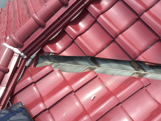 瓦の下に敷き詰められた土（湿式工法）と、変色した銅製の谷板金