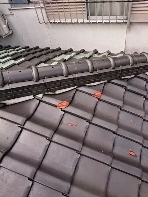 瓦屋根の上に散乱する瓦の破片と葺き土：雨漏りの前兆