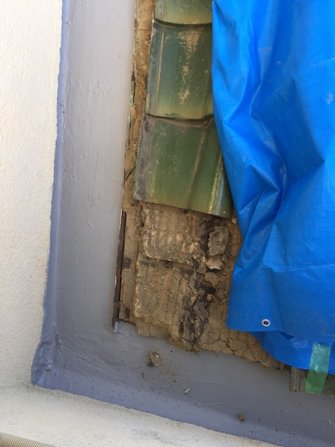 壁際の漆喰崩落と内部の葺き土露出。雨漏りの直接原因。