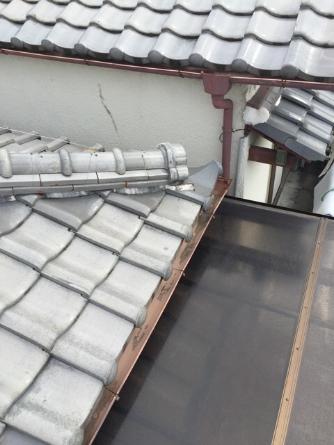 屋根の端部の瓦のズレと、雨樋周辺の排水不良の兆候。