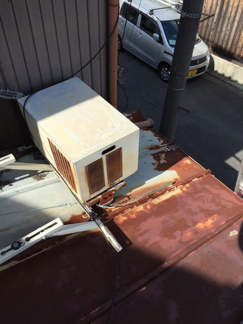 城陽市の現場で確認された、赤錆が進行し腐食した瓦棒屋根とエアコン室外機