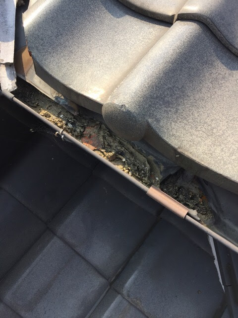 雨樋（雨水を受けるレール）に泥や破片が詰まり、排水機能が完全にストップしている状態