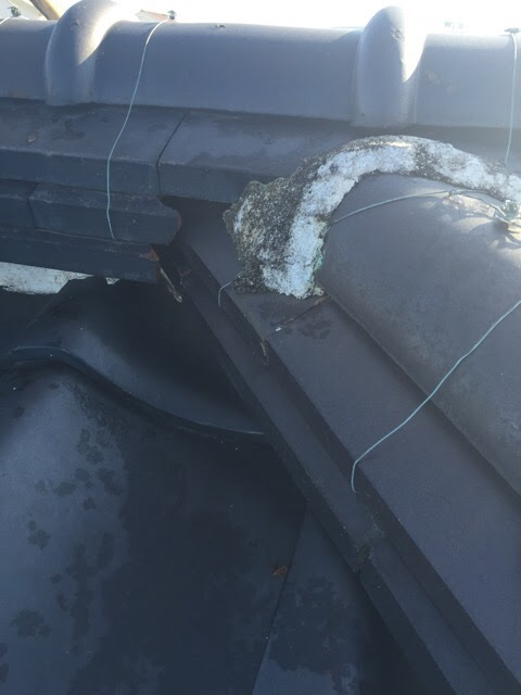 鬼瓦周辺の漆喰（白い詰め物）が黒ずみ、表面が崩れている劣化状況