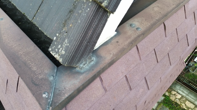 屋根の谷板金（たにばんきん）の接合部。経年劣化により金属部分が変色し、雨水が集中する箇所であるため雨漏りのリスクが高まっている状態。