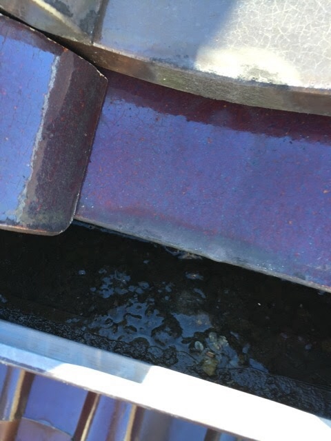 谷樋に水が溜まり、雨水が瓦の下に逆流している危険な状態