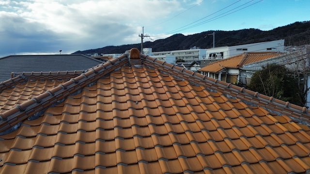 屋根の棟周りの目視点検。のし瓦のズレや鬼瓦周辺の漆喰の劣化状況を確認。背景に見える電線との離隔もチェック。